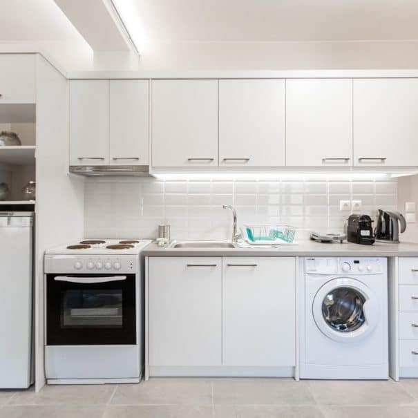 Apartment's kitchen area with many appliances (oven, washing machine, coffee maker etc)